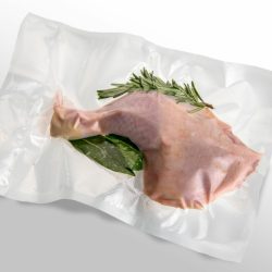 Chicken thigh in vacuum packed sealed for sous vide cooking with rosemary, bay leaf and sage, isolated on white